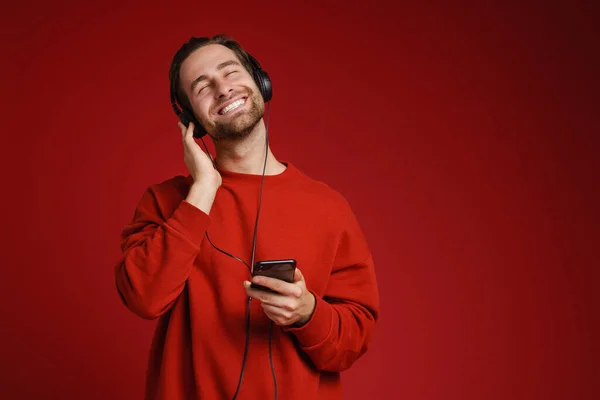 Młody Biały Człowiek Uśmiecha Się Słuchając Muzyki Telefonu Komórkowego Odizolowany — Zdjęcie stockowe