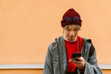 Şehir caddesinde cep telefonu ve kulaklık kullanan Asyalı bir çocuk.