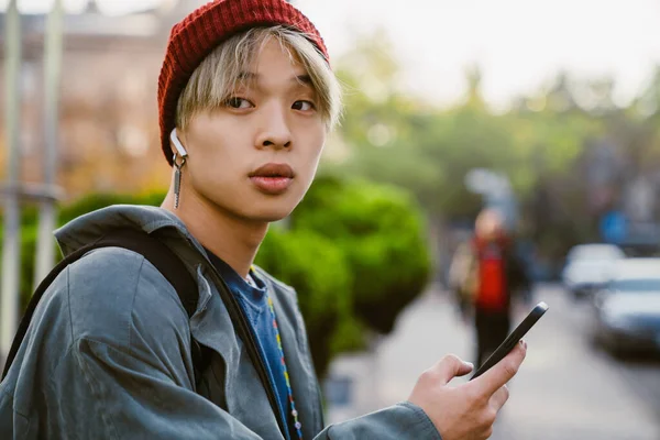 Asijský Chlapec Nosí Klobouk Pomocí Mobilního Telefonu Sluchátek Ulici — Stock fotografie