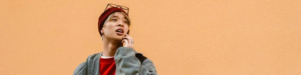 Asijský Chlapec Mluví Mobilním Telefonu Zatímco Stojí Zdi Venku — Stock fotografie