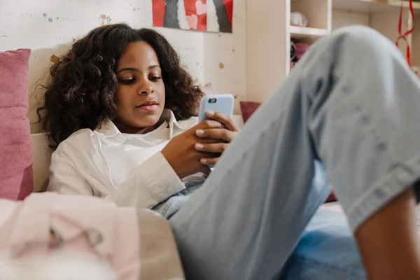 Afrikansk Lugn Tonåring Flicka Som Ligger Säng Med Telefon Sms — Stockfoto