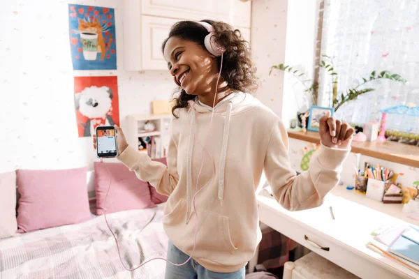 Африканский Счастливый Подросток Наушниках Слушает Музыку Танцует Своей Уютной Комнате — стоковое фото
