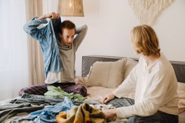 Genç eşcinsel çift evde otururken konuşuyor ve gülümsüyor.