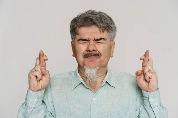 Mature Man Grey Beard Grimacing While Holding Fingers Crossed Isolated — Stock Photo, Image