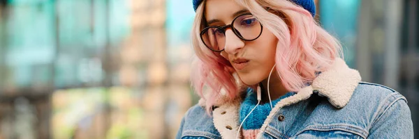 stock image Young woman in eyeglasses listening music while standing outdoors