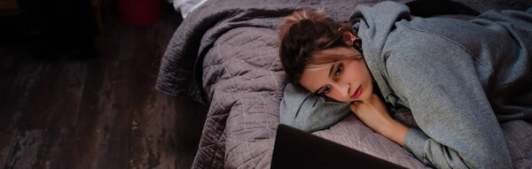 Молодая женщина с тоннелем серьги с помощью ноутбука во время лежания на кровати дома
