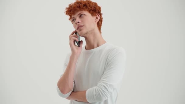 Ένας Κοκκινομάλλης Νεαρός Μιλάει Στο Τηλέφωνο Στο Άσπρο Στούντιο — Αρχείο Βίντεο