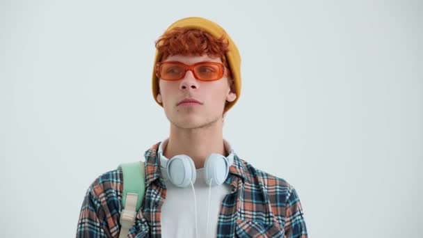 Güneş Gözlüklü Ciddi Kızıl Saçlı Adam Beyaz Stüdyoda Kameraya Seviniyor — Stok video