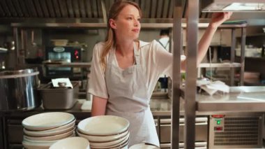 Pozitif kadın şef restoranın mutfağındaki siparişe bakıyor.