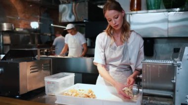 Ciddi sarışın kadın şef restoran mutfağında makarna hazırlıyor.