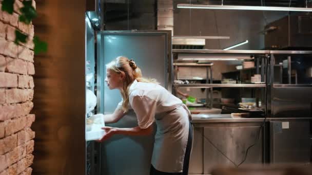 专心致志的金发女厨师从餐厅厨房的冰箱里拿出面条 — 图库视频影像