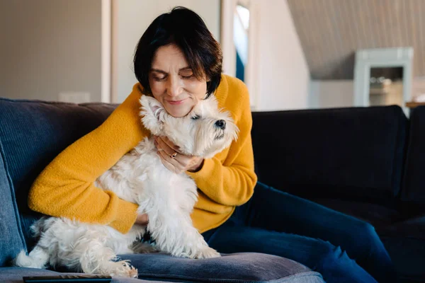 stock image White mature woman hugging her dog while sitting on couch at home