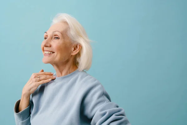 美丽而快乐的老年女性 身穿蓝色套头衫 背负着深蓝色的背景 — 图库照片