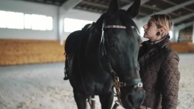 Atı okşayan ve ahırda konuşan güzel bir genç kadın.
