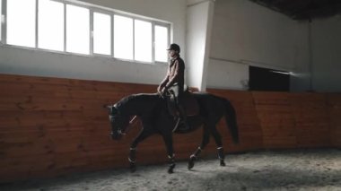 Ahırda ata binen kasklı güzel bir kadın binici.