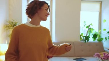 Gözlüklü güzel esmer kadın evde dans ediyor.