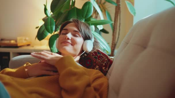 Entspannte Brünette Frau Hört Musik Kopfhörern Auf Dem Sofa Hause — Stockvideo