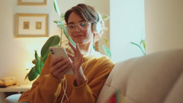 Χαριτωμένη Γυναίκα Ακούγοντας Μουσική Στα Ακουστικά Και Πληκτρολογώντας Στο Κινητό — Αρχείο Βίντεο