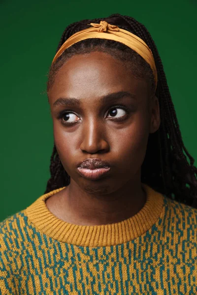 Młoda Czarna Kobieta Afro Warkocze Grymaszenie Patrząc Bok Odizolowane Zielonym — Zdjęcie stockowe