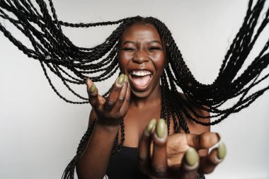 Beyaz arka planda izole bir şekilde kameraya gülümseyen ve el kol hareketi yapan siyah saçlı kadın.