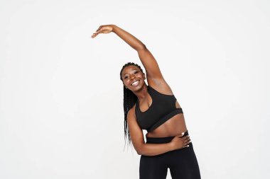 Genç siyah sporcu kadın, beyaz arka planda izole bir şekilde çalışırken egzersiz yapıyor.