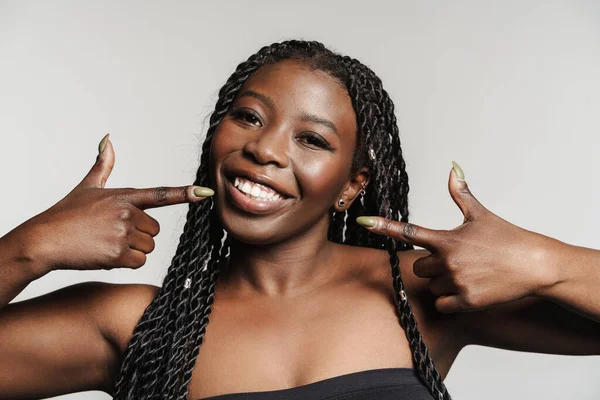 stock image Young black woman with afro pigtails pointing fingers at her smile isolated over grey background