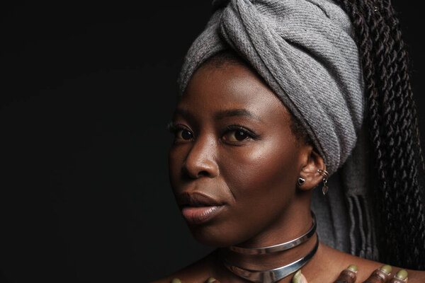 Shirtless black woman wearing headscarf looking at camera isolated over dark background