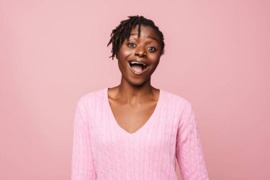 Pembe arka planda izole edilmiş kameraya şaşırdığını ifade eden siyah, heyecanlı kadın.