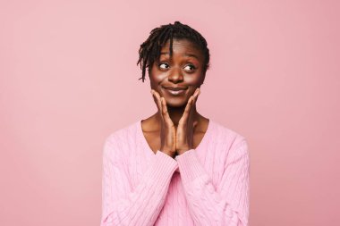 Rasta saçlı, gülümseyen ve pembe arka planda soyutlanmış siyah genç bir kadın.