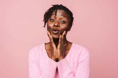 Pembe arka planda izole edilmiş kameraya şaşırdığını ifade eden siyah, heyecanlı kadın.