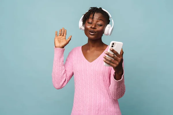 Afroamerikansk Ung Kvinna Ler När Använder Mobiltelefon Och Hörlurar Isolerade — Stockfoto