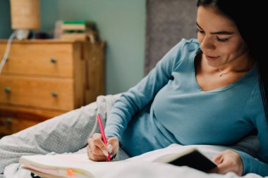 Genç İspanyol kadın evde yatakta yatarken organizatöre notlar yazıyor.