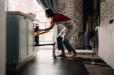 Evde mutfakta önlük giyen İspanyol bir kadın yemek pişiriyor.