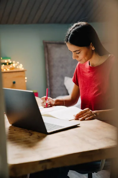 Young Hispanic Woman Writing Notes While Working Laptop Home — ストック写真