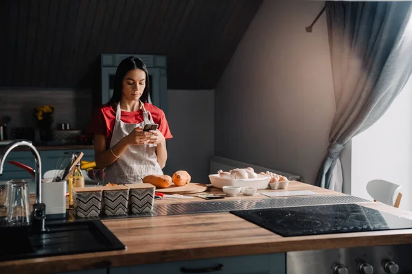 Молодая Испаноязычная Женщина Фартуке Помощью Мобильного Телефона Время Приготовления Пищи — стоковое фото