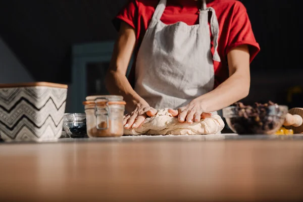 stock image Young woman wearing apron cooking and kneading dough in kitchen at home