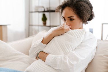 Genç siyahi kadın üzgün ve kürtajı düşünüyor evde kanepede otururken