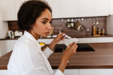 Genç siyahi bir kadın hamilelik testi yaptırırken üzgün.