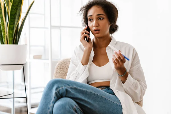 Молодая Черная Женщина Расстроена Держа Тест Беременность Разговаривая Мобильному Телефону — стоковое фото