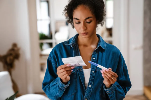 Young Black Woman Holding Pregnancy Test Instruction Home — Stock Photo, Image