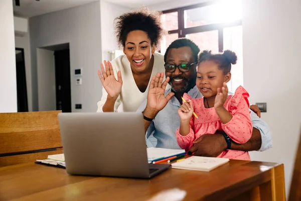 非洲裔美国人家庭 小女孩坐在桌旁 一边笑着一边在笔记本电脑前挥手 — 图库照片