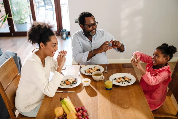 Afroamericana Familia Mujer Hombre Con Pequeña Hija Sonriendo Desayunando Casa —  Fotos de Stock