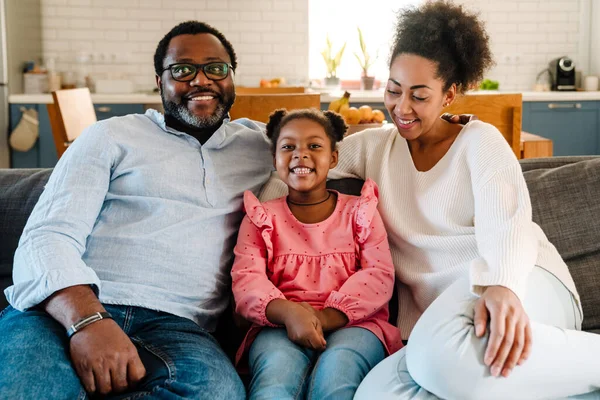 Afroamericana Familia Mujer Hombre Con Pequeña Hija Sonriendo Sentado Sofá —  Fotos de Stock
