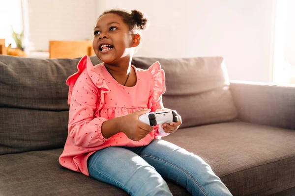 Niña Afroamericana Sentada Sofá Jugando Videojuegos Con Controlador Casa —  Fotos de Stock