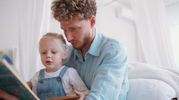 Серьезный Блондин Отец Дочь Читают Книгу Дома — стоковое видео