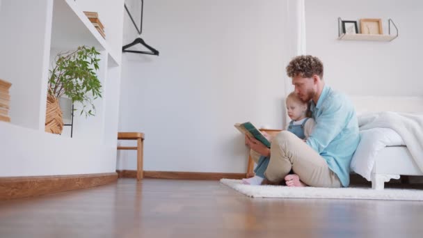 漂亮的父亲和女儿在房子的地板上看书 — 图库视频影像