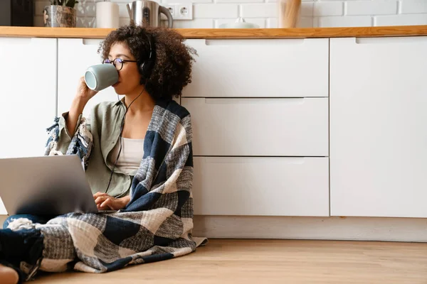 非洲裔美国妇女 头发卷曲 喜欢喝咖啡 在家使用笔记本电脑 — 图库照片