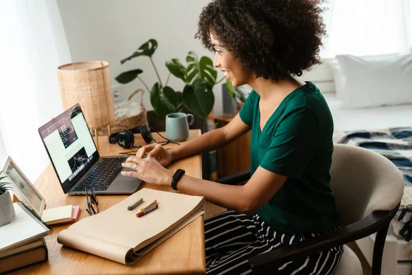 非洲裔美国女青年 卷曲的非洲式发型坐在办公桌前 在家里用笔记本电脑 — 图库照片