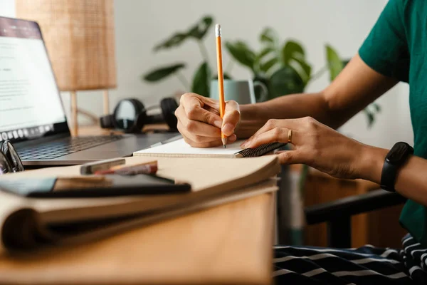 アフリカ系アメリカ人の若い女性がラップトップを使用してノートを取りながら机に座って — ストック写真