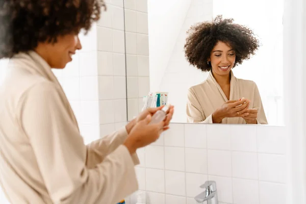 Kıvırcık Saçlı Gülümseyen Banyoda Deri Toniği Tutan Afro Amerikalı Genç — Stok fotoğraf